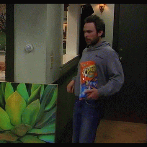 Man Holding Bag Of Cheetos In Front Of Plant Painting GIF