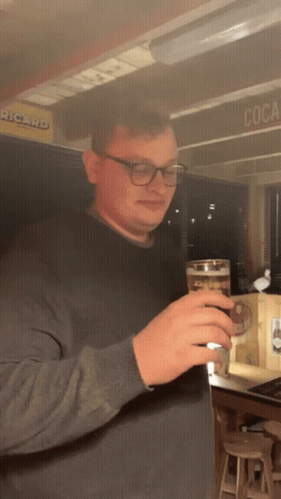Man Holding Beer In Front Of Ricard Sign GIF