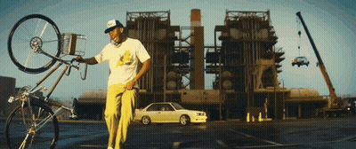 Man Holding Bicycle In Front Of Building With Parked Car GIF