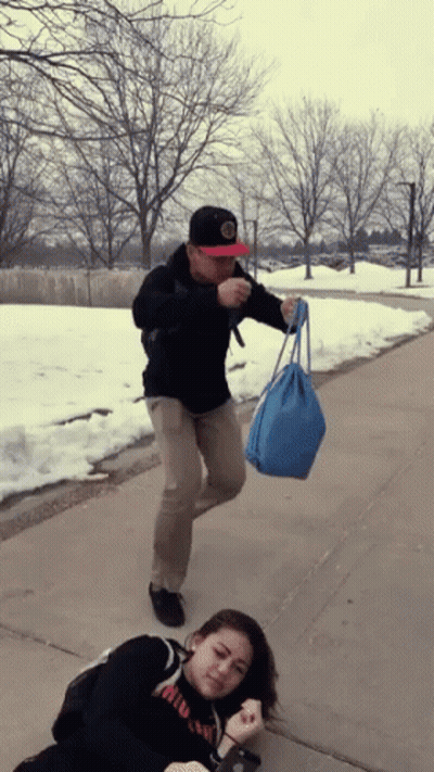 Man Holding Blue Bag While Woman Lays On Ground GIF