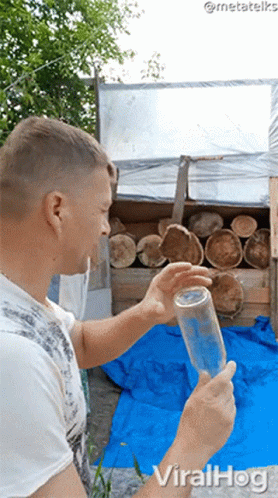 Man Holding Bottle In Front Of Logs With Viralhog GIF