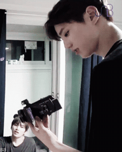 Man Holding Camera In Front Of Window With Letter B On Ear GIF