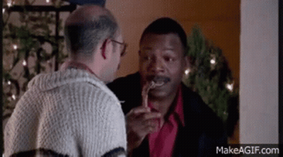 Man Holding Candy Cane In Mouth Talking To Another Man GIF