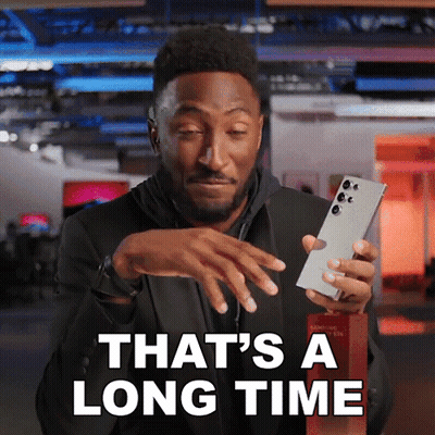 Man Holding Cell Phone Saying That's a Long Time