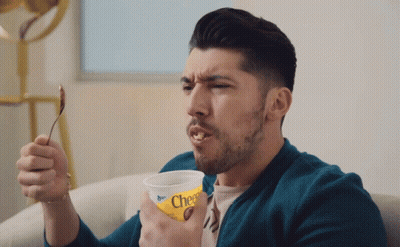 Man Holding Cheerios Cup With Spoon In Mouth GIF