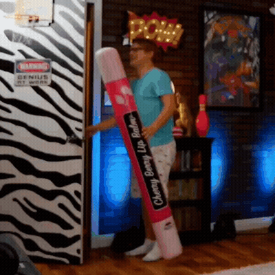 Man Holding Cherry Berry Lip Balm In Front Of Zebra Door GIF