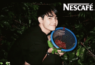 Man Holding Coffee Beans in Front of Nescafe Sign