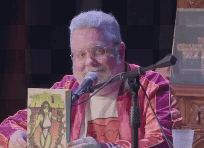 Man Holding Comic Book At Microphone Chicago Talk GIF