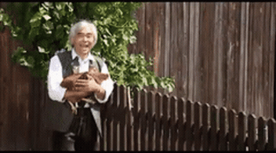 Man Holding Dog In Front Of Fence GIF