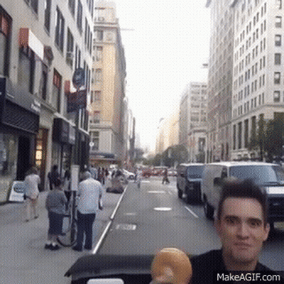 Man Holding Donut On City Street GIF
