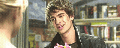 Man Holding Flower in Front of Woman Smiling