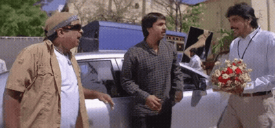 Man Holding Flowers Talking To Two Men GIF