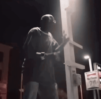 Man Holding Gun At 7 Eleven Sign Night GIF