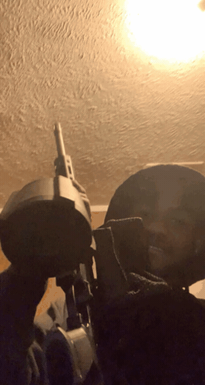 Man Holding Gun In Dark Room With Light Through Ceiling GIF