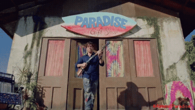 Man Holding Gun In Front Of Paradise Gift Shop GIF