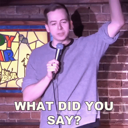Man Holding Microphone In Front Of Brick Wall Saying What Did You Say GIF