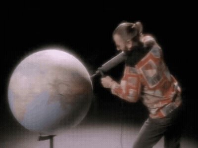 Man Holding Microphone In Front Of Globe GIF