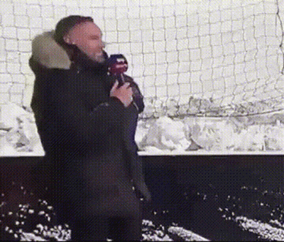 Man Holding Microphone In Front Of Snowy Fence GIF