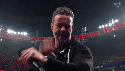 Man Holding Microphone In Front Of WWE Live Sign GIF