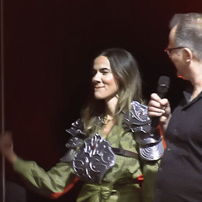 Man Holding Microphone Next to Woman in Armor