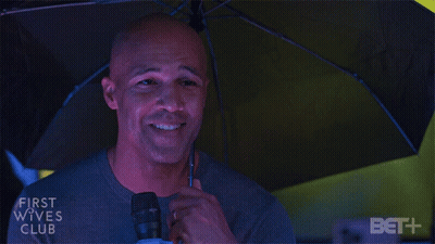 Man Holding Microphone Under First Wives Club Umbrella GIF