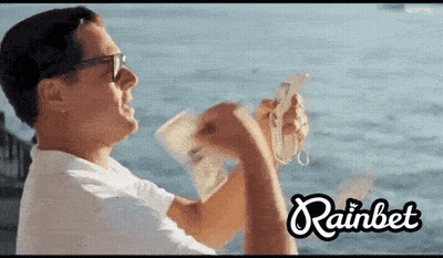 Man Holding Money in Front of Ocean Rainbet