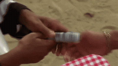 Man Holding Money On Woman's Wrist At Beach GIF