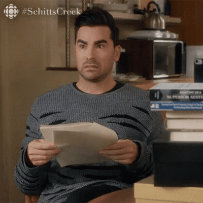 Man Holding Paper In Front Of Books Schitts Creek GIF