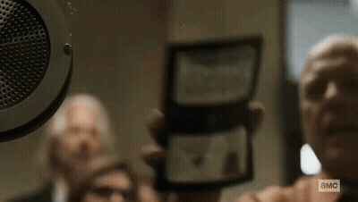 Man Holding Paper Saying A.M.C. In Front Of Speaker GIF