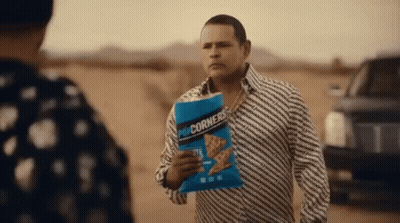 Man Holding Popcorn Talking To Another In Desert GIF