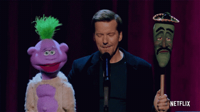 Man Holding Purple And Green Puppets With Sombrero GIF
