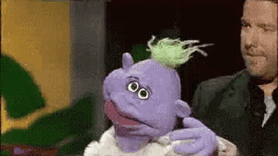 Man Holding Purple Puppet With Green Hair GIF