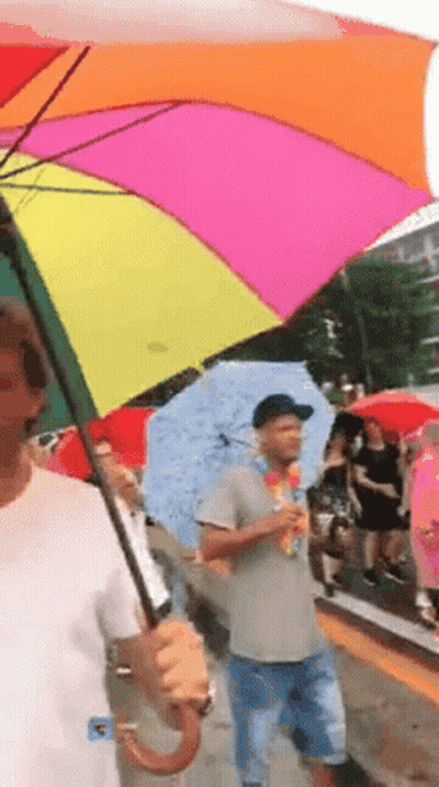 Man Holding Rainbow Umbrella Walking