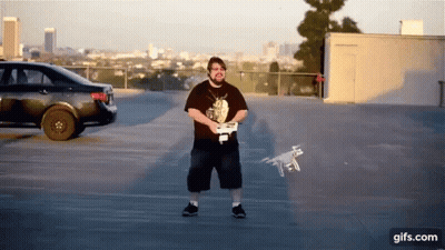 Hombre con control remoto y dron volando en estacionamiento GIF