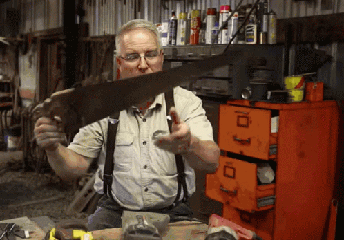 Man Holding Saw In Front Of Orange Filing Cabinet With Letter D GIF