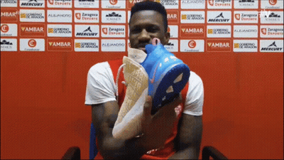 Man Holding Shoes In Front Of Ambar Wall GIF