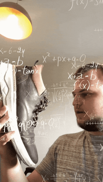 Man Holding Shoes In Front Of Chalkboard With Math Equations GIF