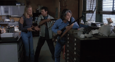 Man Holding Shotgun Next To Woman And Man In Messy Room GIF