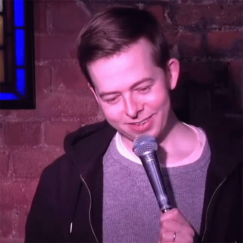 Man Holding Shure Microphone In Front Of Brick Wall GIF