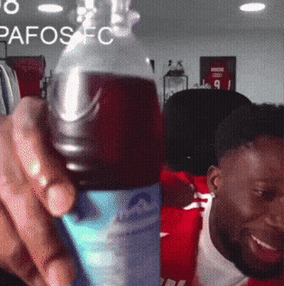 Man Holding Soda In Front Of Pafos FC Sign GIF