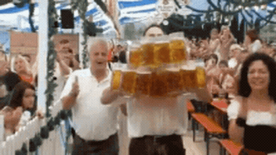 Man Holding Stack Of Beer Mugs In Front Of Crowd GIF