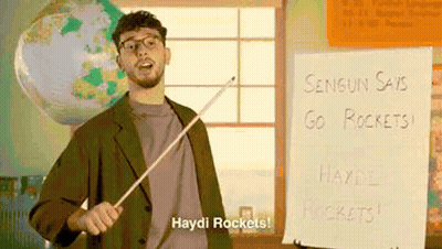 Man Holding Stick In Front Of Haydi Rockets Sign GIF