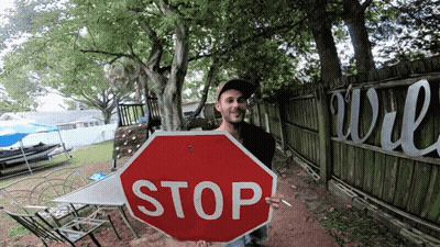 Man Holding Stop Sign In Front Of Fence GIF