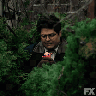 Man Holding Stuffed Animal Behind Bush With FX Logo GIF
