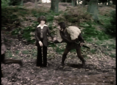 Man Holding Sword And Woman Holding Sheep In Woods GIF