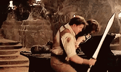 Man Holding Sword In Cave Woman On Table GIF