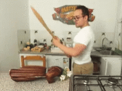 Man Holding Sword In Front Of Mattel Sign GIF