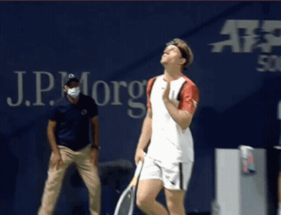 Man Holding Tennis Racquet In Front Of JP Morgan Sign GIF