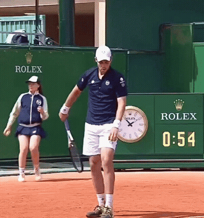 Man Holding Tennis Racquet In Front Of Rolex Wall GIF