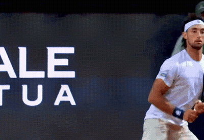 Man Holding Tennis Racquet In Front Of Wall Saying Le Ua GIF